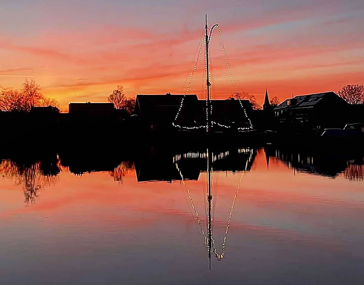 Skûtsje bijna verzwolgen in vlammenzee van ondergaande zon