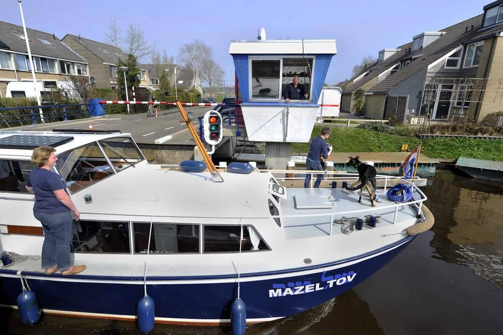 Brugwachter Gerrit van Marrum van de Weidlânsbrug in Akkrum gooit zijn klompje uit om twee euro aan bruggeld te vangen. De opvarenden van het de motorboot Mazeltov maken op een van de eerste mooie voorjaarsdagen een vaartochtje over de Friese wateren.