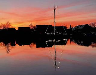 Skûtsje bijna verzwolgen in vlammenzee van ondergaande zon