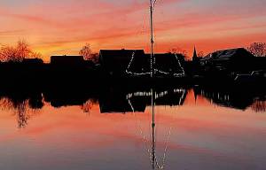 Skûtsje bijna verzwolgen in vlammenzee van ondergaande zon